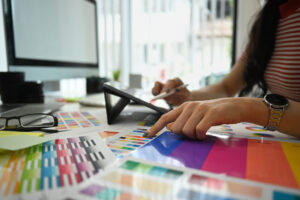 Closeup view female designer working with color palette, choosing color samples for design project at modern office.